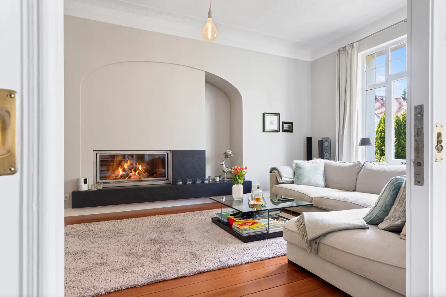 Living room with a fireplace, a gray sofa, a glass table, and a light bulb hanging from the ceiling.