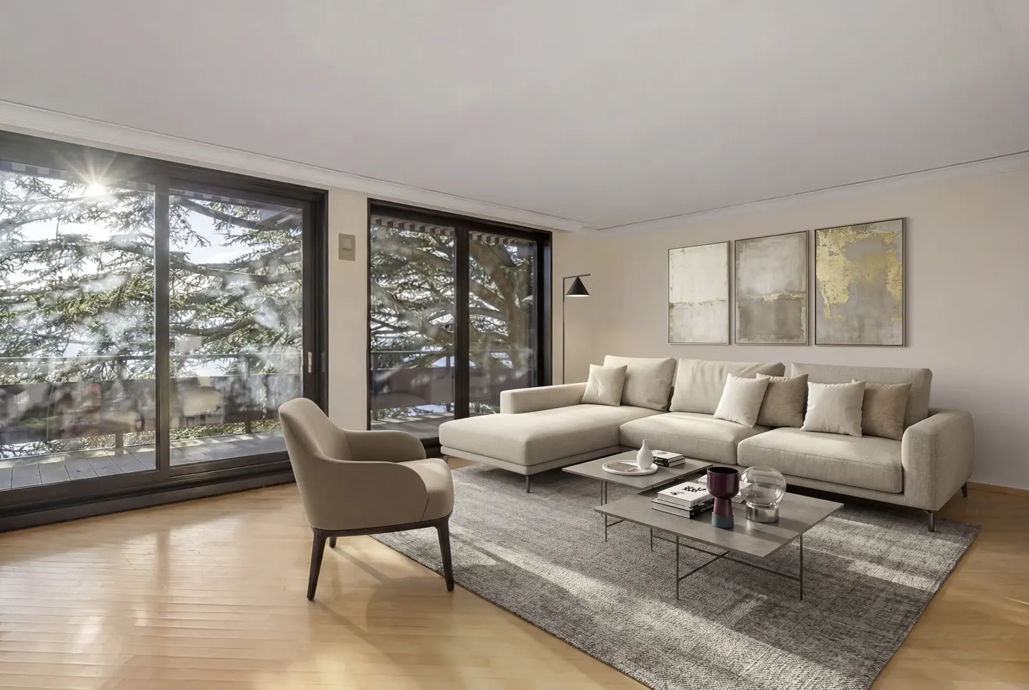 Bright living room with beige sectional sofa, armchair, and gray rug. Large windows offer a view of trees and sunlight.