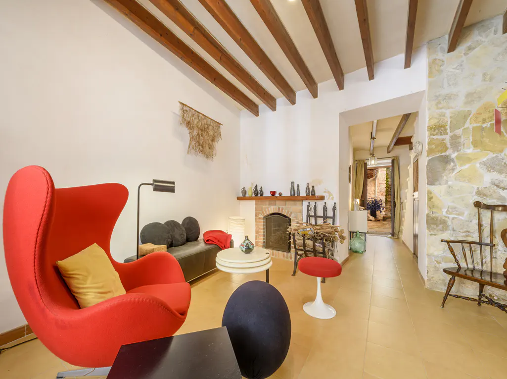A living room with a red egg chair, a black sofa, a fireplace, and a stone wall.