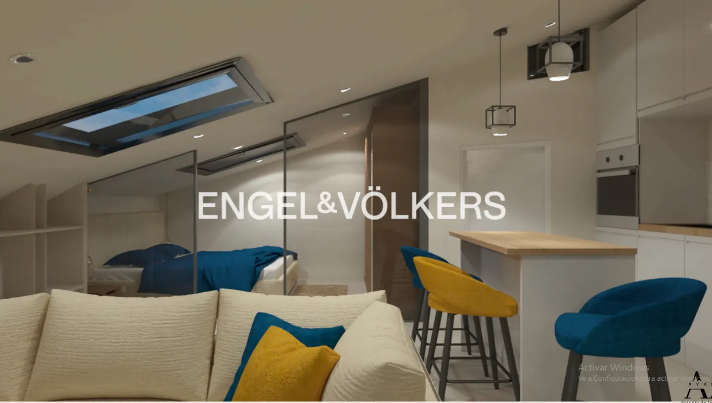 Bright apartment interior with skylights, featuring a cream sofa with blue and yellow pillows, a kitchen island, and Engel & Völkers logo.