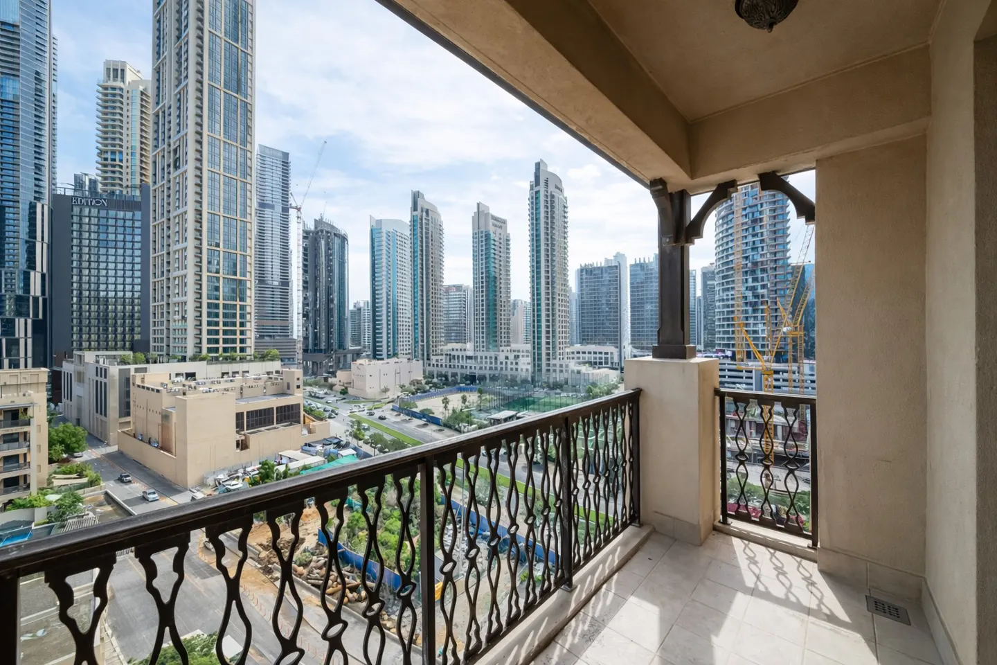 View from a balcony with black metal railings overlooking a city with tall buildings.