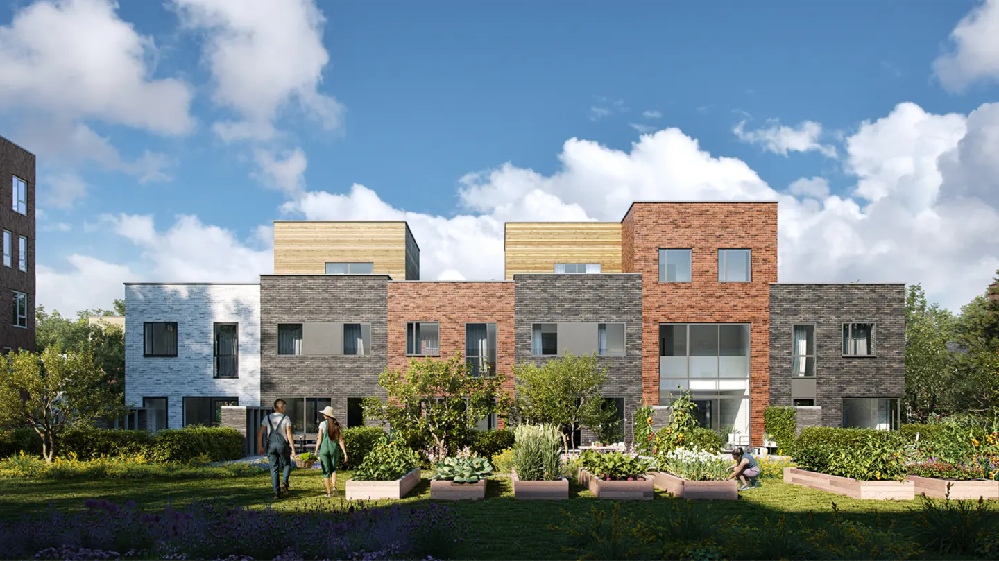 Modern brick townhouses with wooden accents overlook a lush community garden with raised beds and people walking outside.