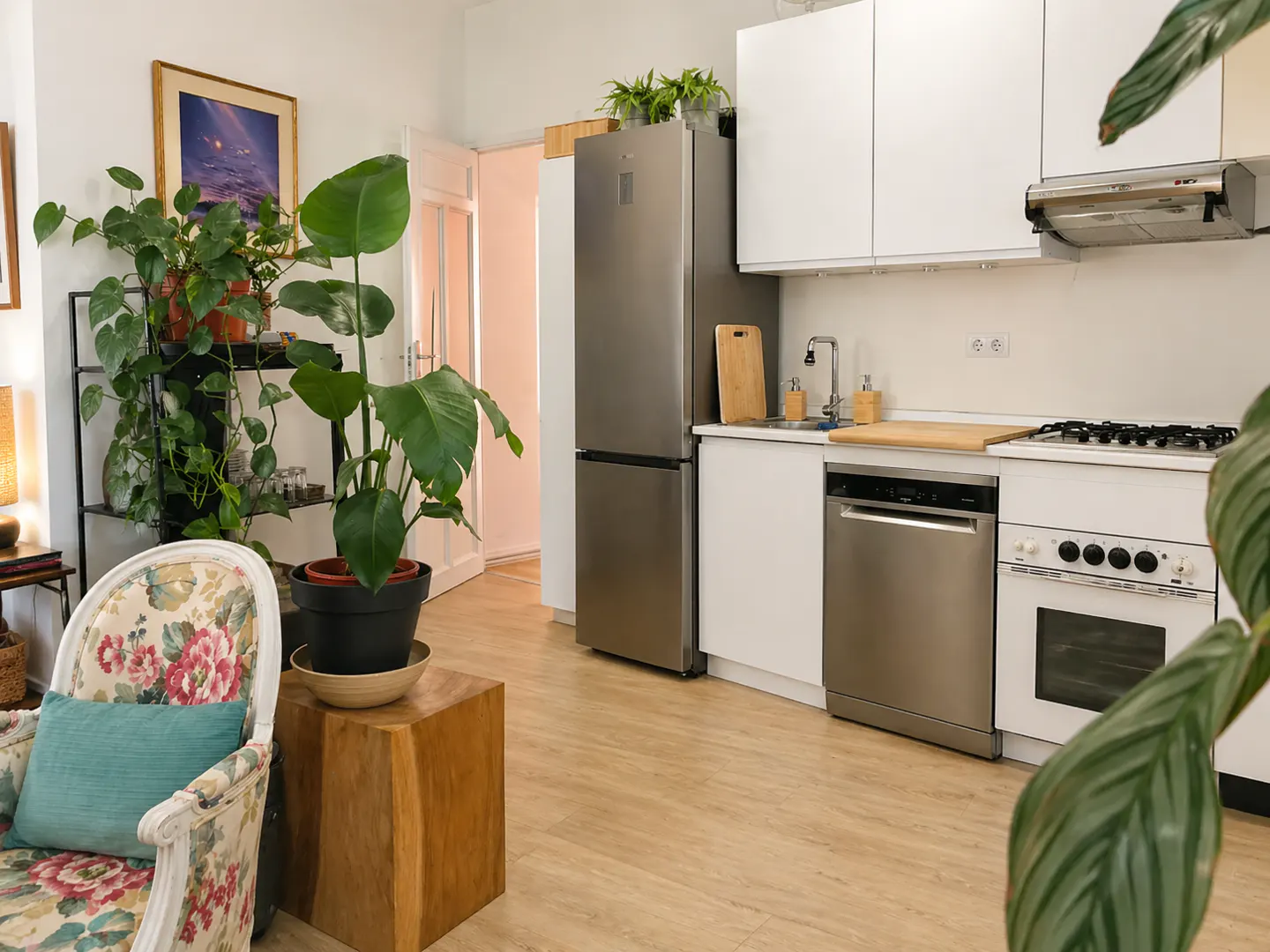 Bright kitchen with stainless steel appliances, white cabinets, and light wood floors. Plants add a touch of nature to the space.