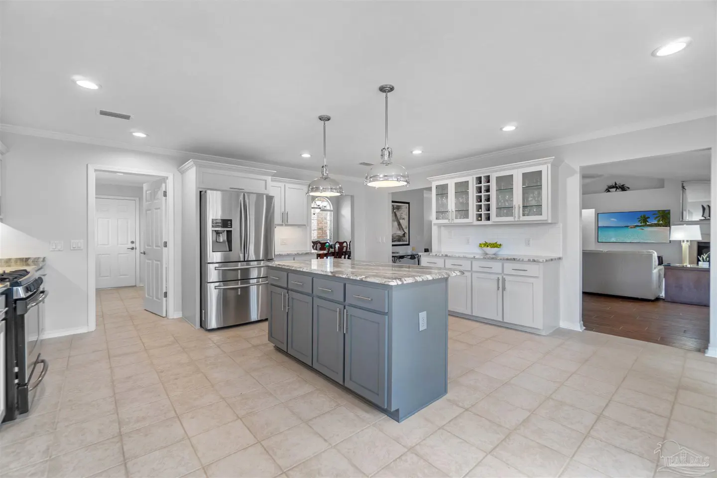Modern kitchen with white cabinets, a grey center island, stainless steel appliances, and tile flooring.