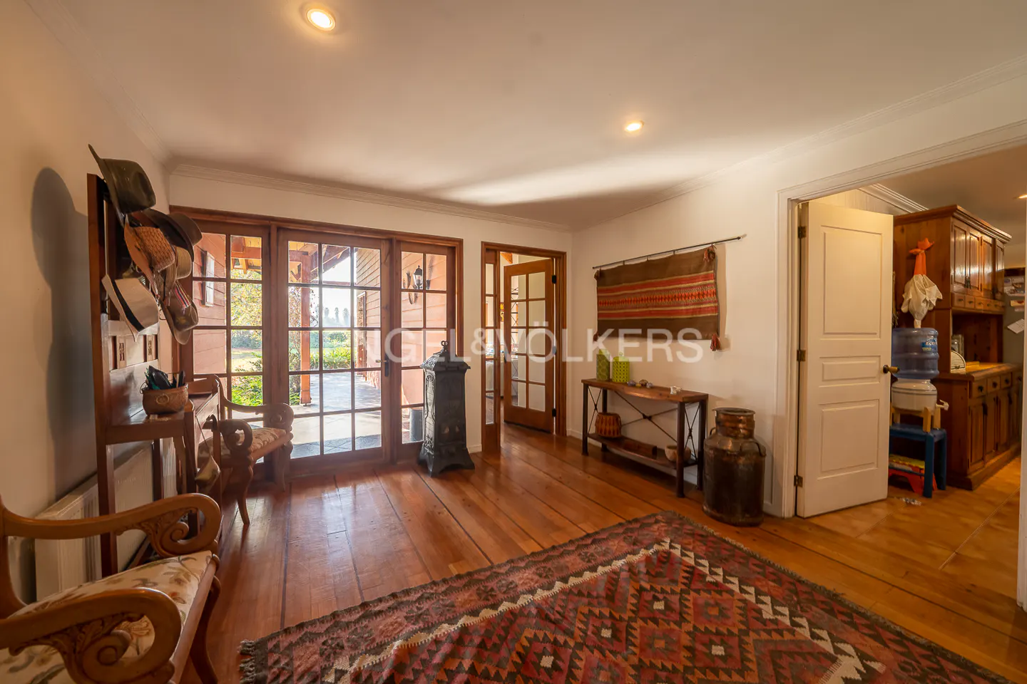 A bright foyer with wood floors, a patterned rug, and a hat rack. French doors lead to a patio.
