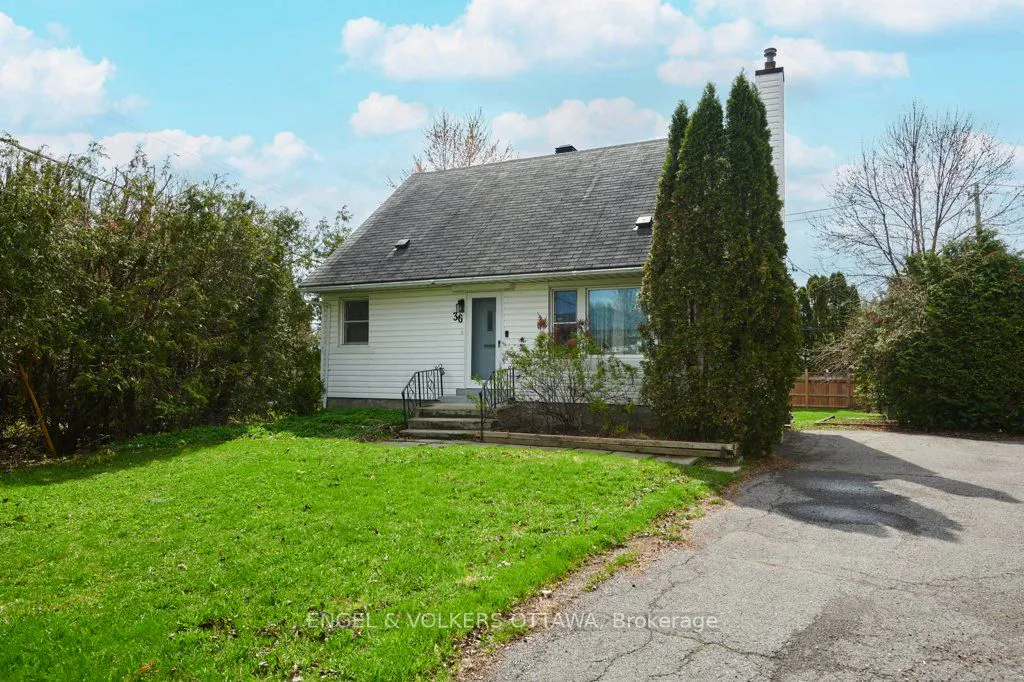 Exterior of a white, one-story house with a gray roof, green lawn, and driveway on a sunny day.
