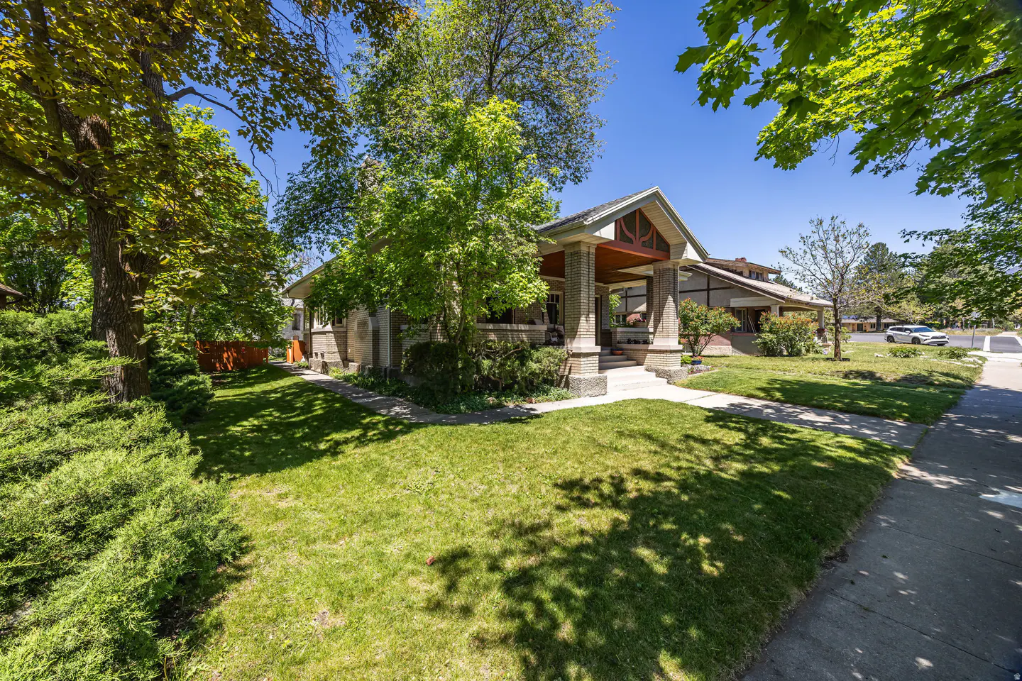 A single-family home with a brick porch and green lawn on a sunny day.