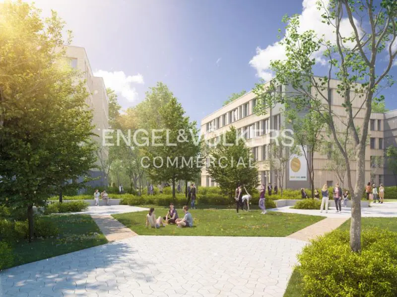 Exterior view of a commercial building with a green space, trees, and people. The sky is blue with some clouds. "Engel & Volkers Commercial" is overlaid.