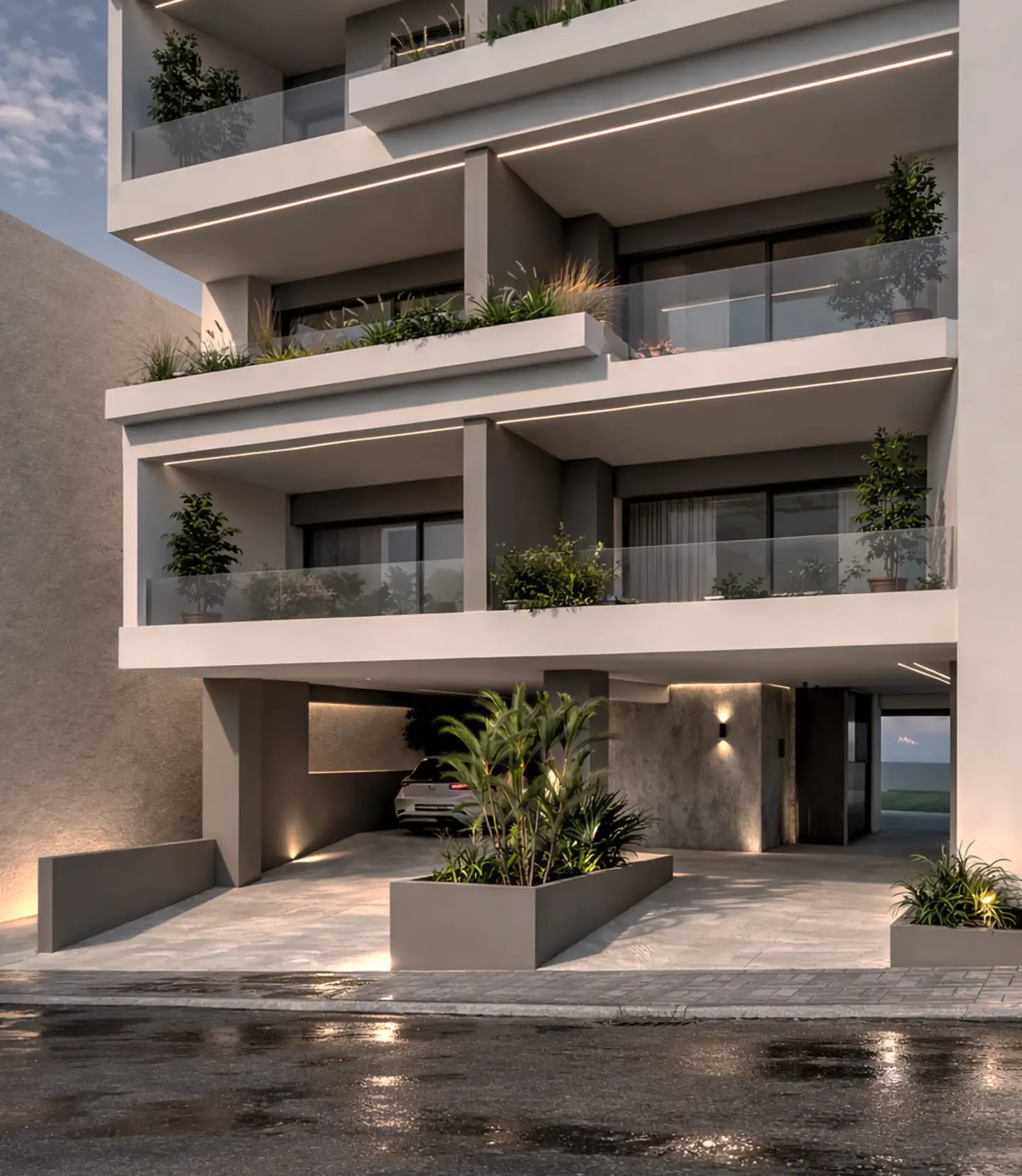 Modern apartment building with gray facade, glass balconies, and greenery. A car is parked in the covered garage.
