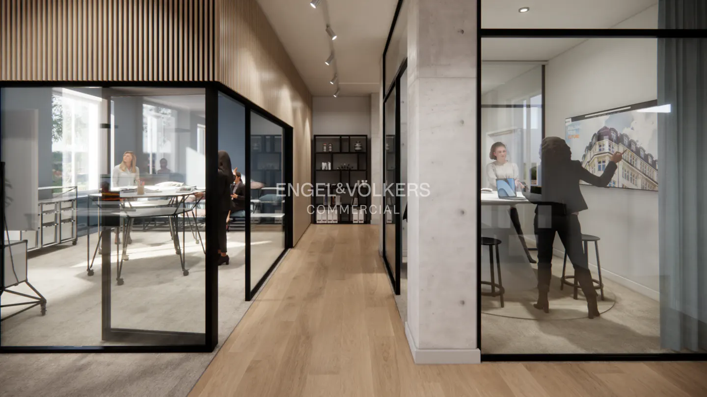 Office interior with glass-walled rooms. People are working at tables. The Engel & Volkers logo is visible in the hallway.