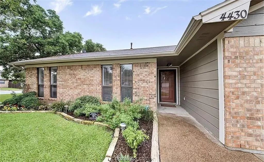 A single-story brick house with a brown door and a well-manicured lawn. The house number "4430" is visible above the entrance.