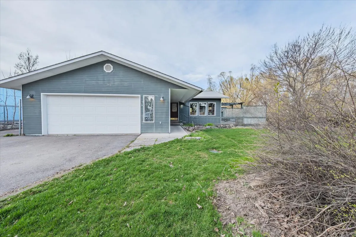 A single-story, light blue house with a white garage door and green lawn.