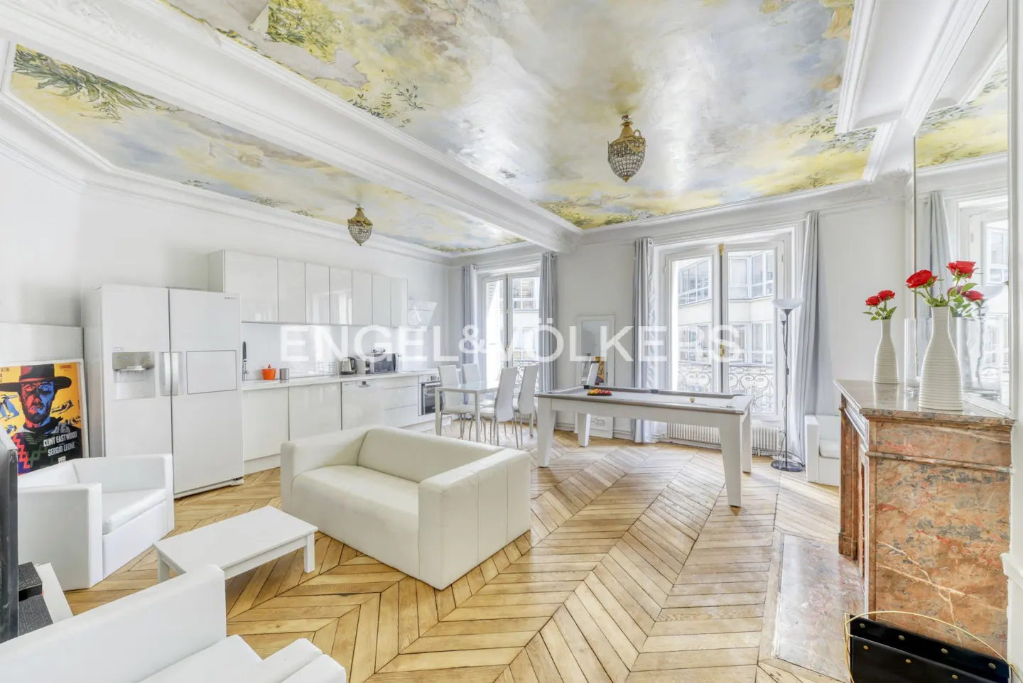 A bright, open-concept apartment with white furniture, a pool table, and a painted ceiling.