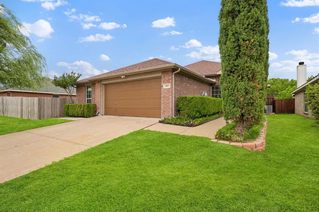 A single-story brick house with a brown roof, a brown garage door, green bushes, and a green lawn.