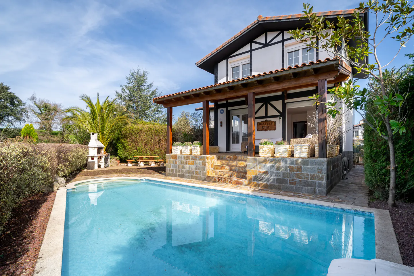 Exterior view of a two-story house with a pool, stone steps, and a covered porch. The house is white with black trim.