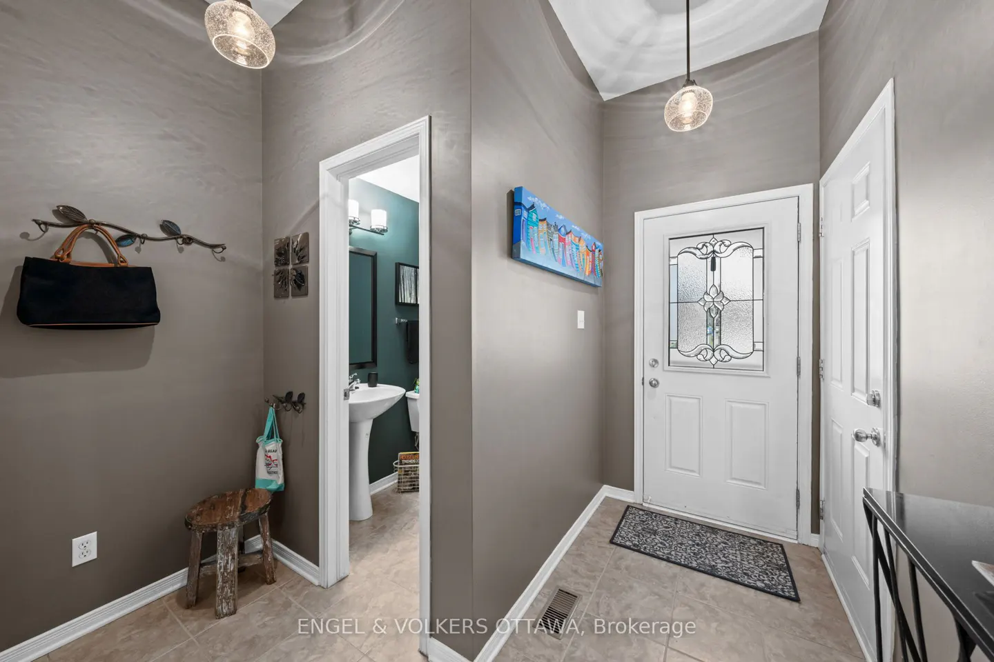 Foyer with gray walls, tile floor, and white trim. A white front door with glass is visible. A powder room is to the left.