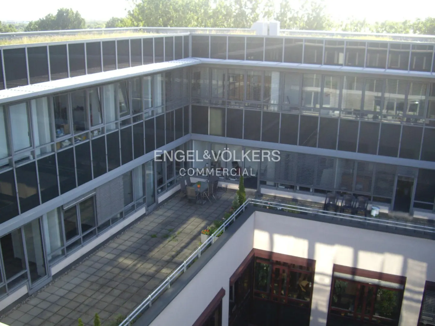 Exterior view of a modern commercial building with a rooftop terrace and Engel & Völkers Commercial logo.
