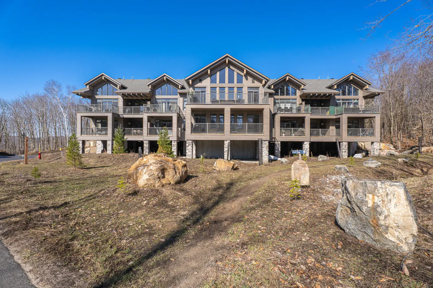 Three-story condo building with balconies, stone accents, and large windows on a sunny day.