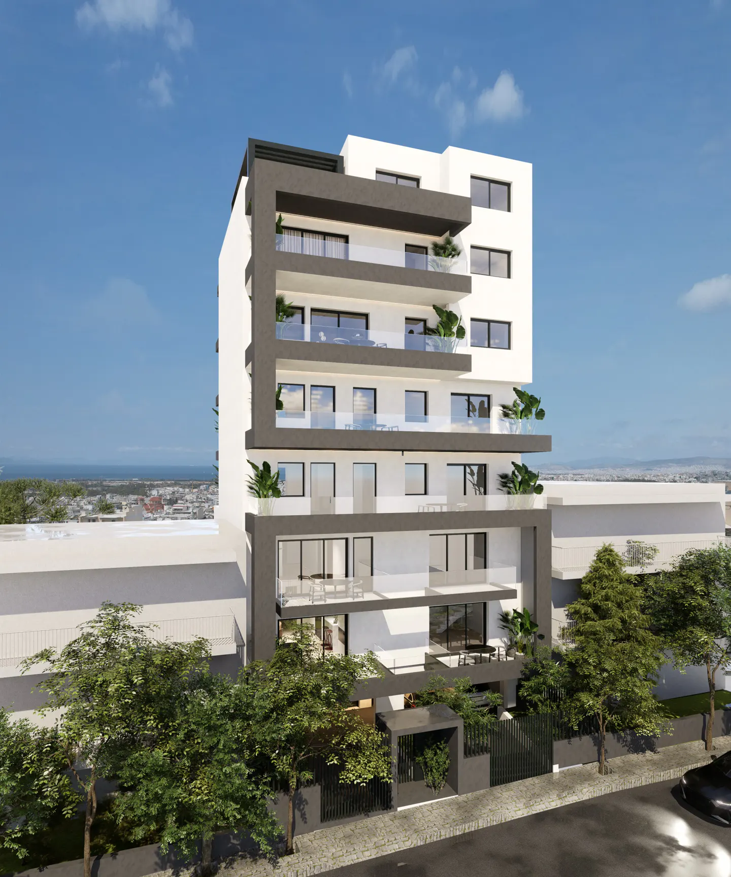 Modern white apartment building with gray trim and glass balconies, set against a blue sky and trees.