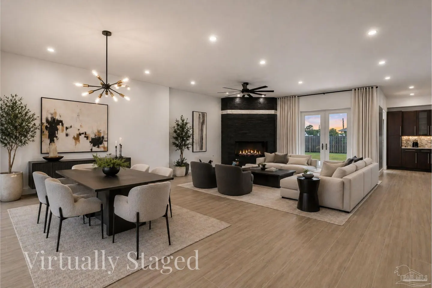 Open-concept living space with dining table, black fireplace, and beige sofa. Wood-look flooring and neutral color palette.