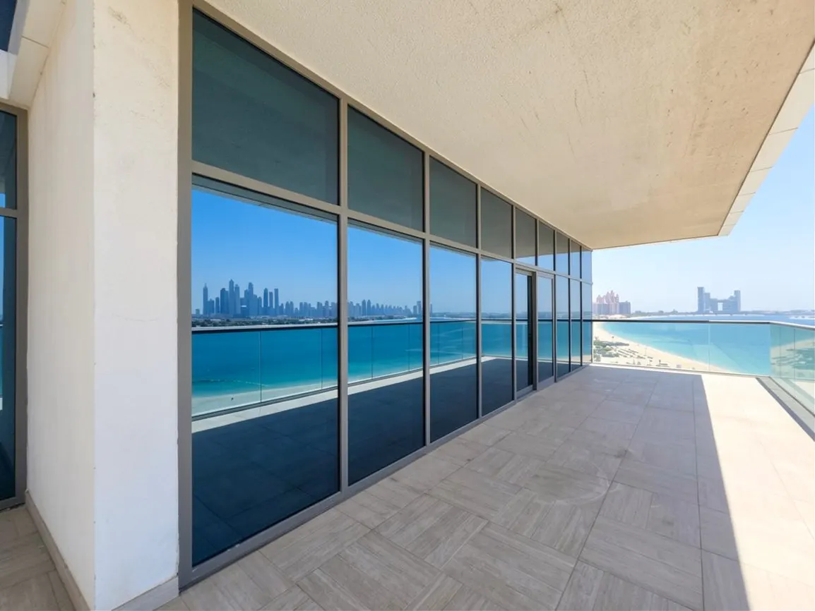 Spacious balcony with tiled floor and glass railings, reflecting a panoramic view of the Dubai skyline and blue ocean.