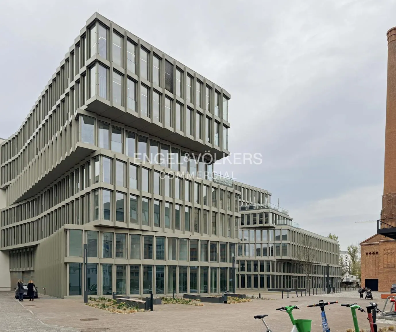 Modern office building with large windows and a stepped design, plus scooters parked nearby.