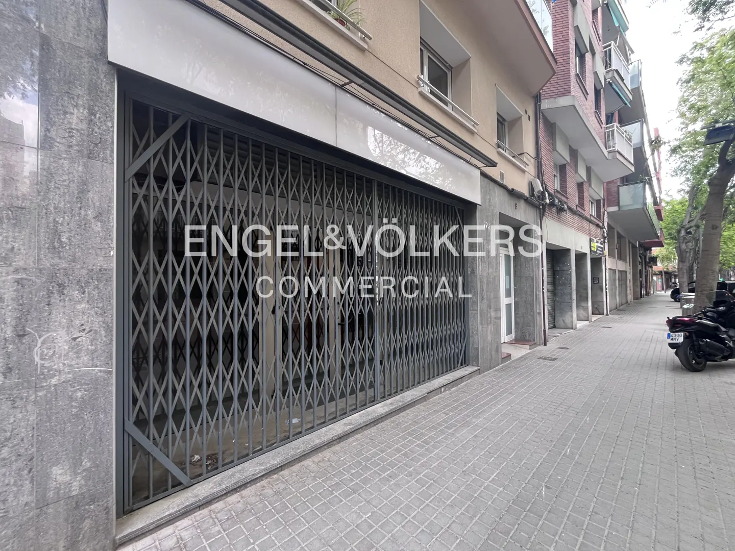 Exterior of a commercial property with a gray metal security gate and Engel & Völkers Commercial signage.