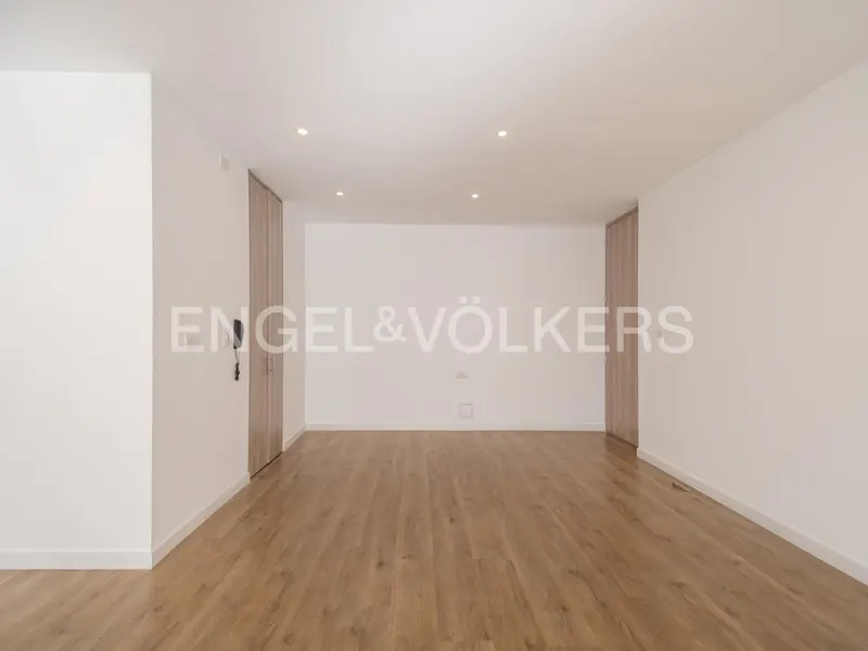 Empty room with light wood floors, white walls, and recessed lighting. Two light wood closets flank the back wall. Engel & Völkers logo visible.
