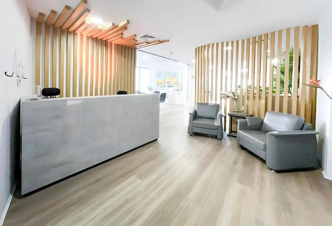 Modern office reception area with a gray desk, wooden slats on the walls and ceiling, and gray seating.