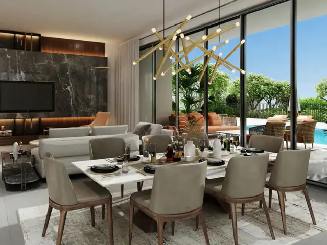 A modern dining room with a white table, gray chairs, and a gold chandelier. Sliding glass doors open to a patio with a pool.