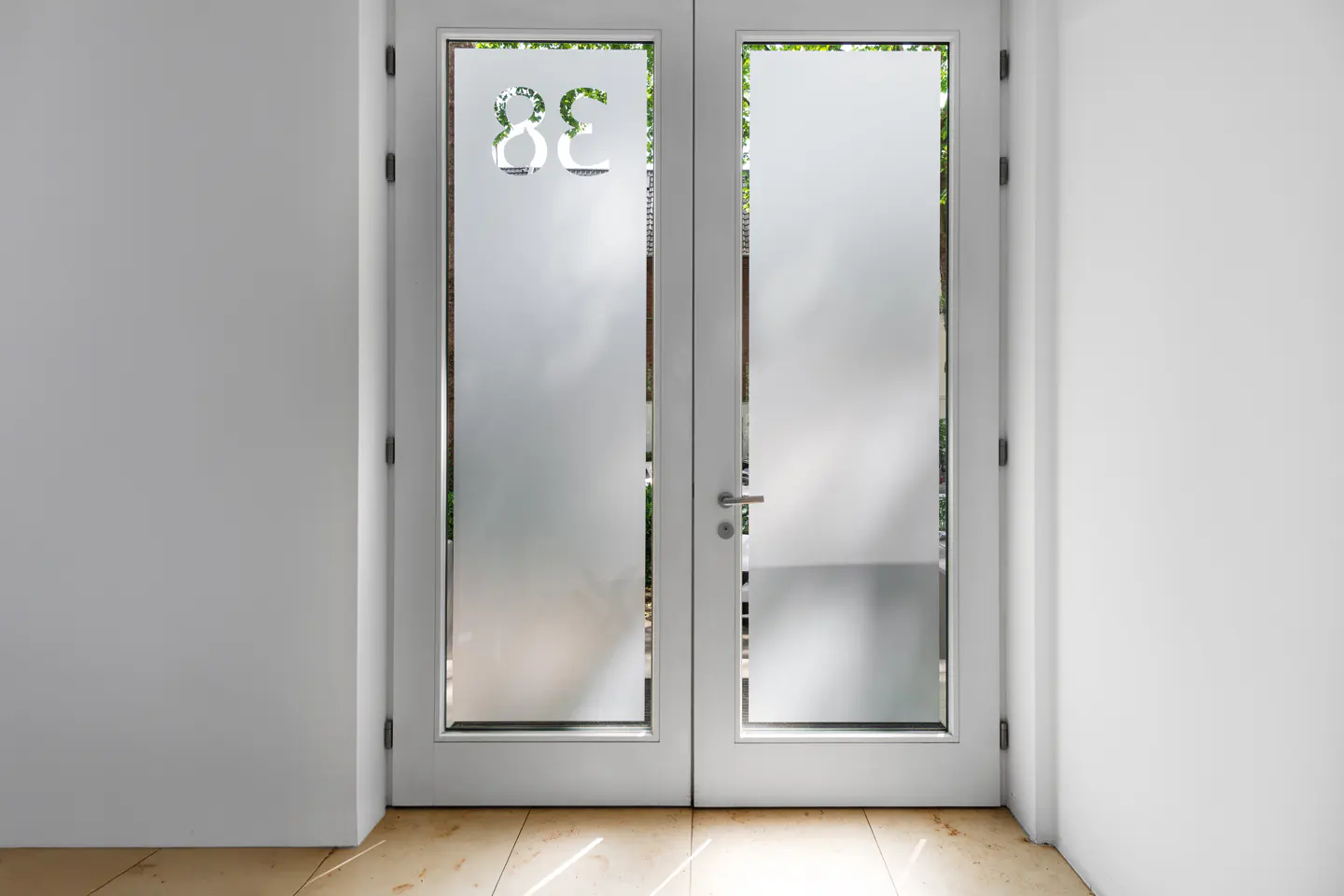 White double doors with frosted glass and "38C" address. Light brown tile floor and white walls.