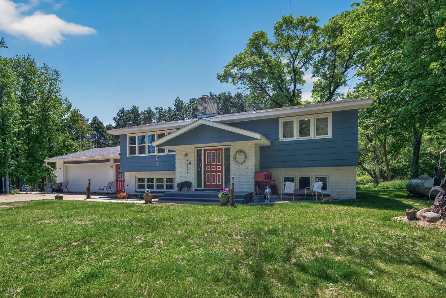 Two-story home with blue siding and white brick, red front door, and green lawn.