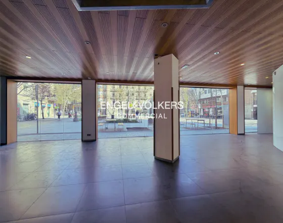 Empty commercial space with wood ceiling, gray tile floor, and large windows showing a city street.