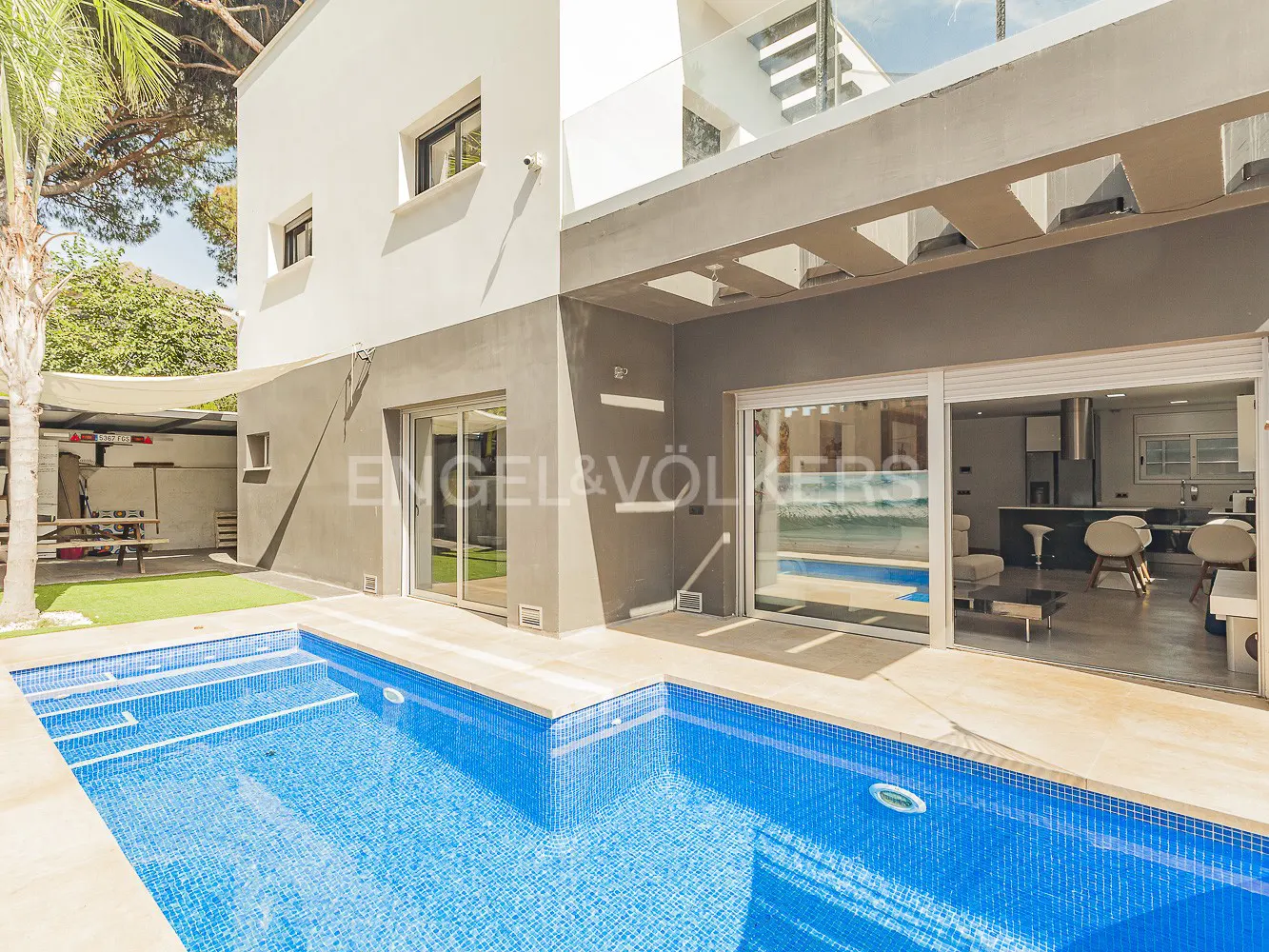 Exterior view of a modern two-story house with a blue tiled pool and sliding glass doors.