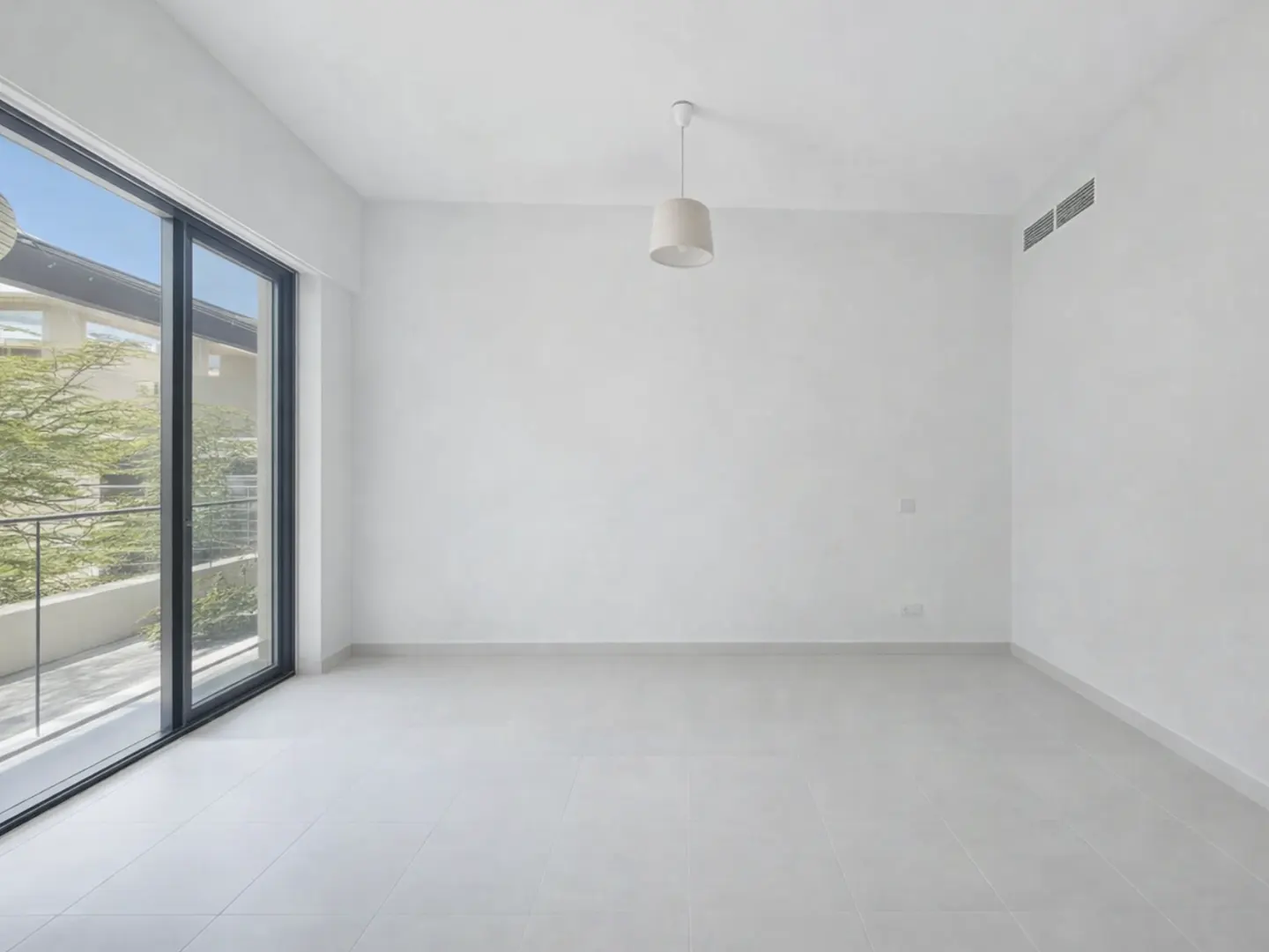 An empty, bright room with white walls, light gray tile floor, and a large sliding glass door to a balcony.