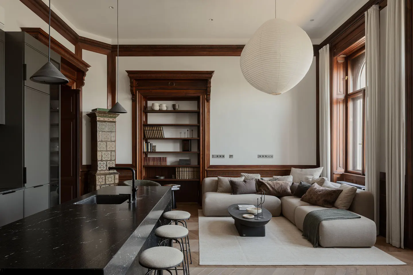 Open-concept living space with dark wood trim, a black marble island, and a beige sectional sofa. A large paper lantern hangs from the ceiling.