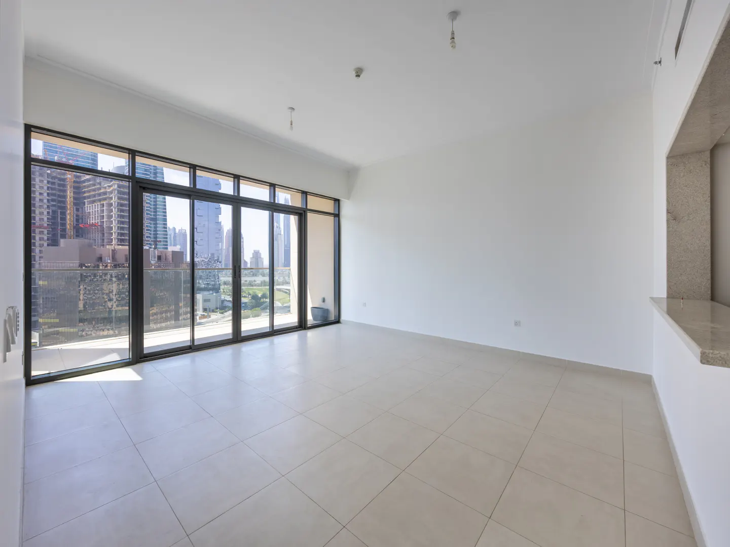 Empty room with beige tile floor, white walls, and a large window with a city view.