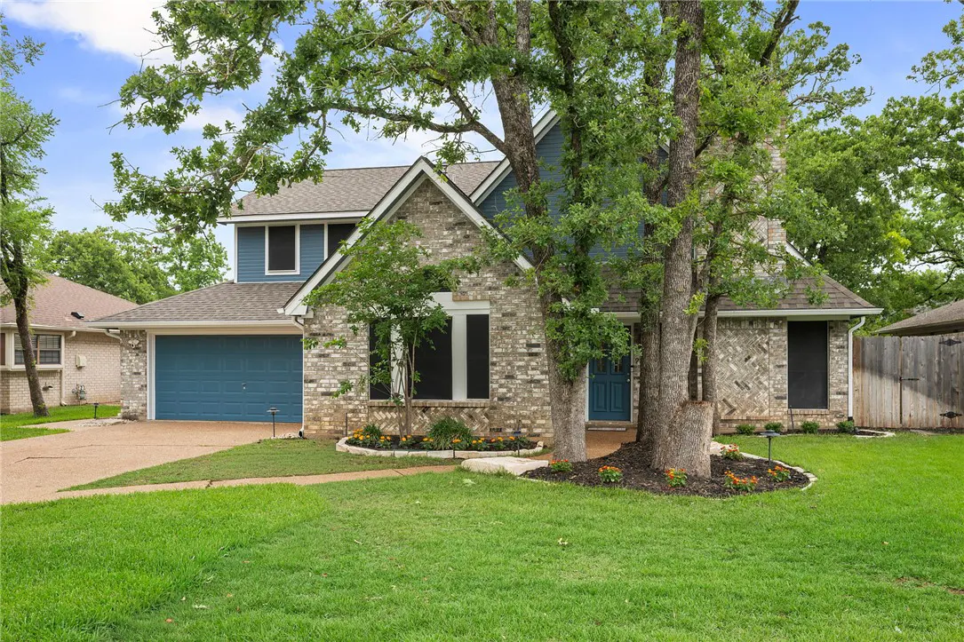 Two-story brick house with blue accents, a blue garage door, and a well-manicured lawn. Trees frame the house.