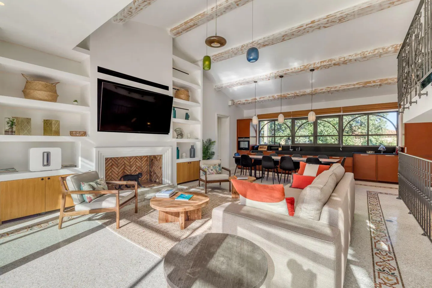 Bright, open-concept living room with a fireplace, TV, and built-in shelves. A large sofa and dining table are visible.