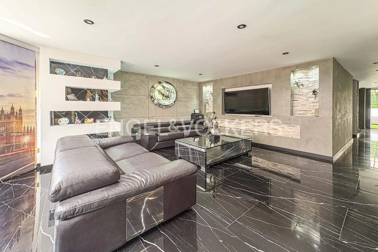 Modern living room with black marble floors, dark leather sofas, a glass coffee table, and a wall-mounted TV.