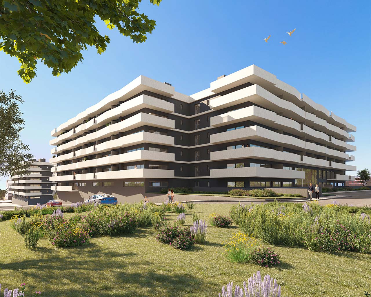 Modern apartment building with white balconies and dark gray walls, surrounded by green lawn and colorful flowers.