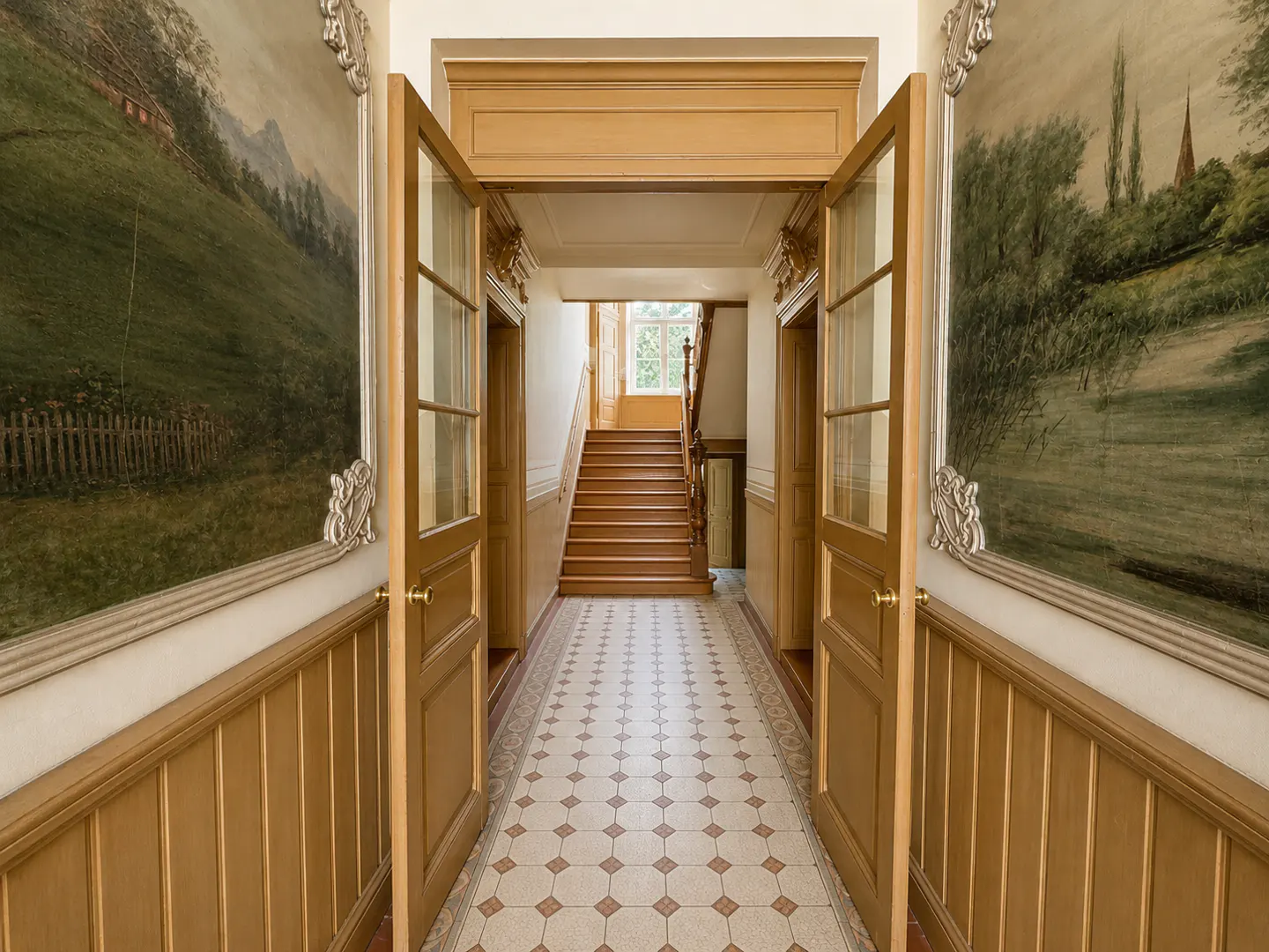 Hallway with tiled floor, open wooden doors, and large landscape paintings on walls leading to a wooden staircase.