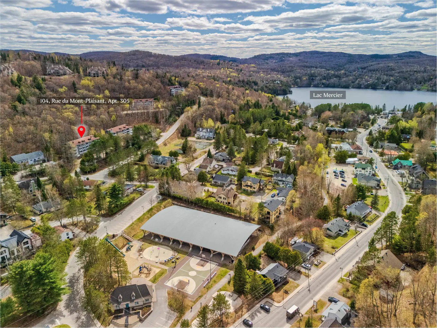 Aerial view of a residential area with houses, trees, a playground, and Lac Mercier in the background. A red marker indicates "104, Rue du Mont-Plaisant, Apt. 305".