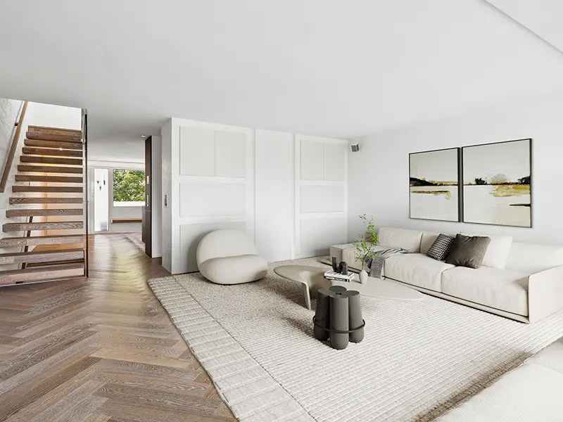 Bright living room with wood floors, white walls, and a staircase. A white sofa, chair, and rug create a cozy space with modern art on the wall.