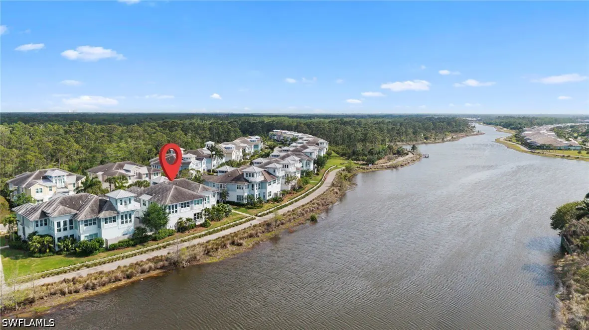 Aerial view of light blue townhouses along a river, with a red location pin on one of the roofs.
