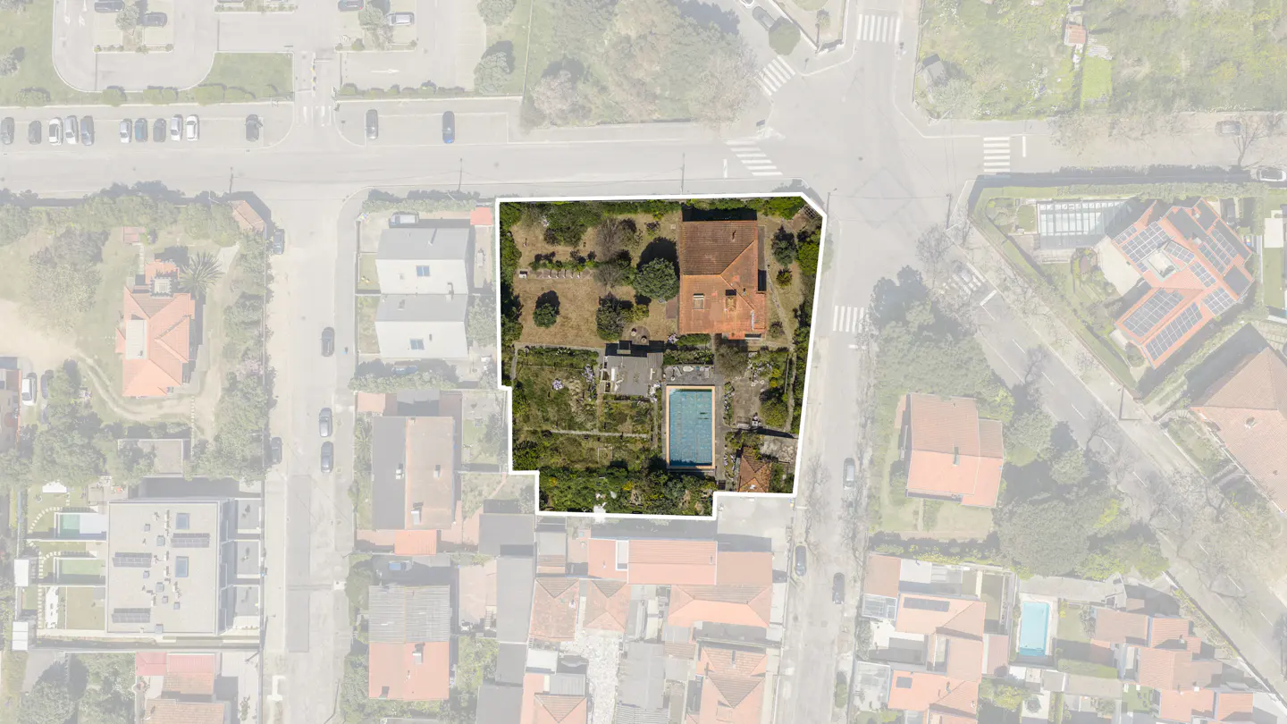 Aerial view of a property outlined in white, featuring a house with a red tile roof, a pool, and a garden.