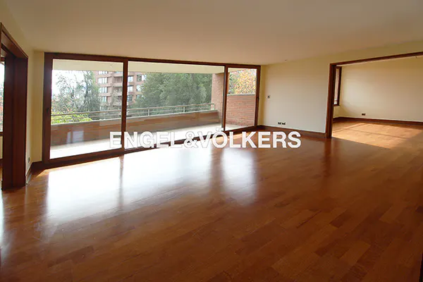 Empty living room with hardwood floors, large sliding glass doors to a balcony, and an open doorway to another room.