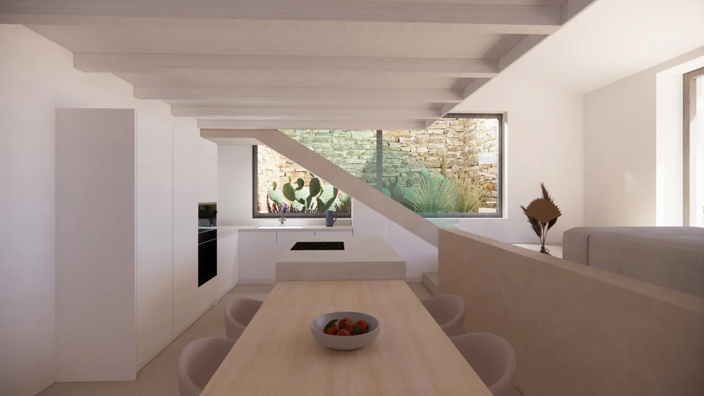 Bright, modern kitchen with white cabinets, wood table, and pink chairs. A bowl of fruit sits on the table. A large window shows a stone wall and cacti.