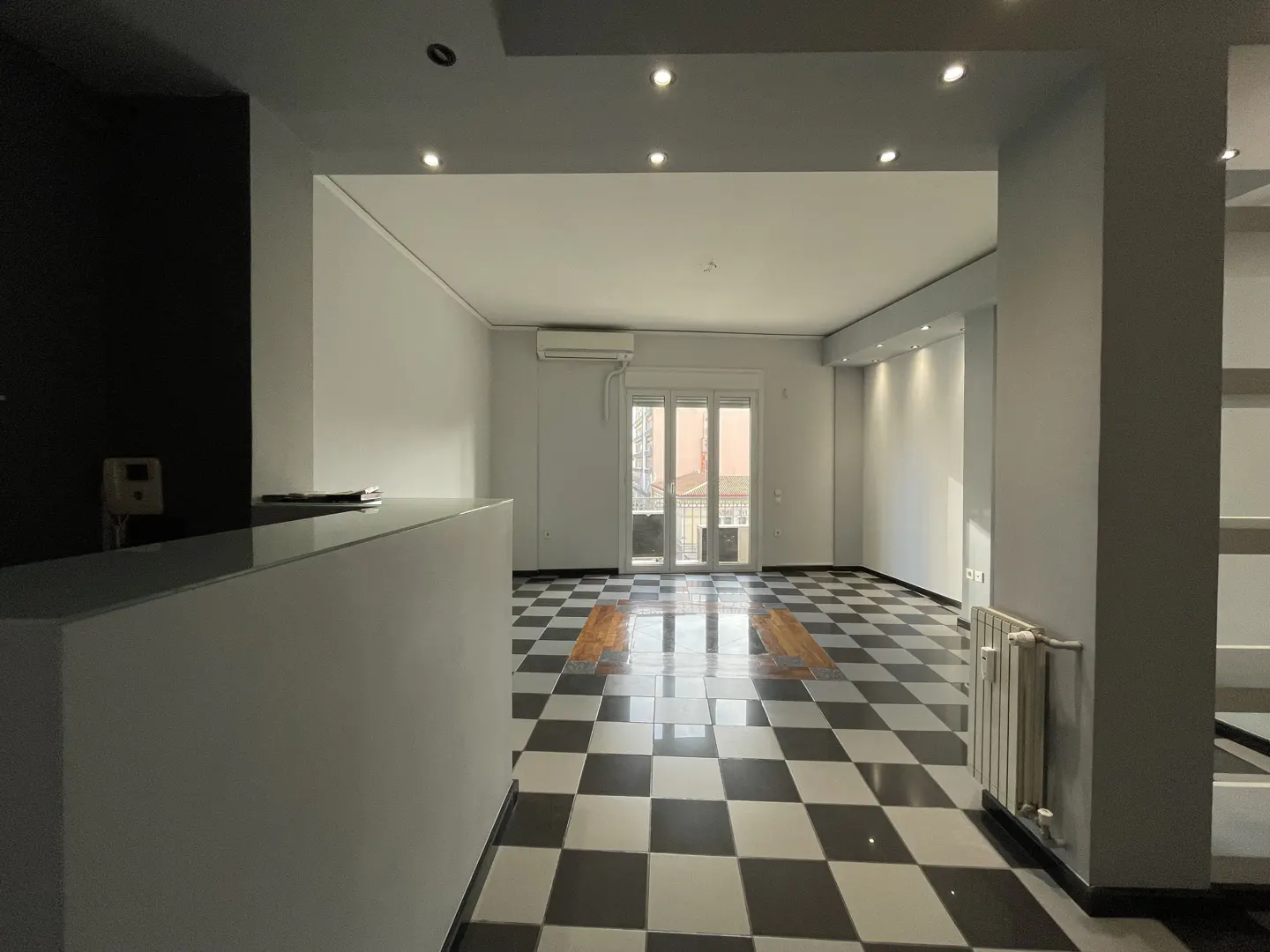 A bright, empty room with black and white checkered floors and a white reception desk.