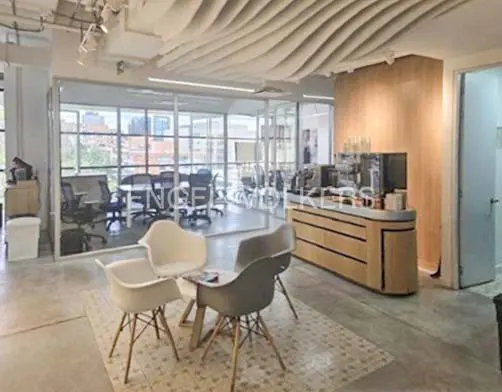 Office space with white chairs, a wooden counter, and a glass-walled conference room. The ceiling has a wavy design.